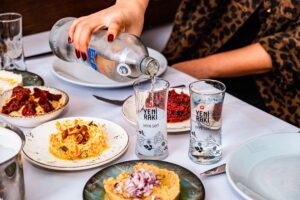 A vibrant display of Turkish meze dishes with Yeni Rakı being served, capturing the essence of an İstanbul dining experience.